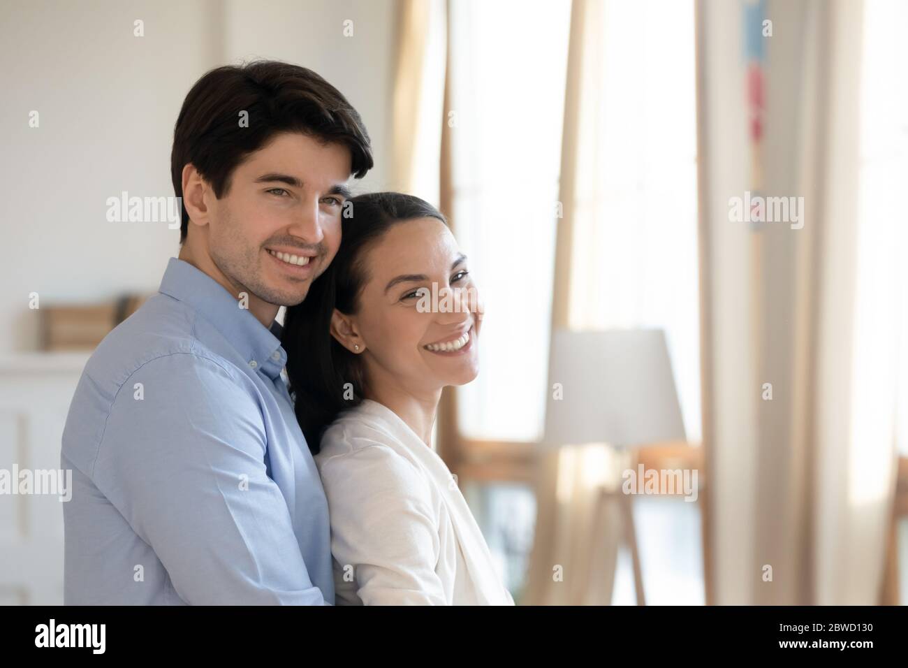 Happy young couple stand in new home hugging Stock Photo