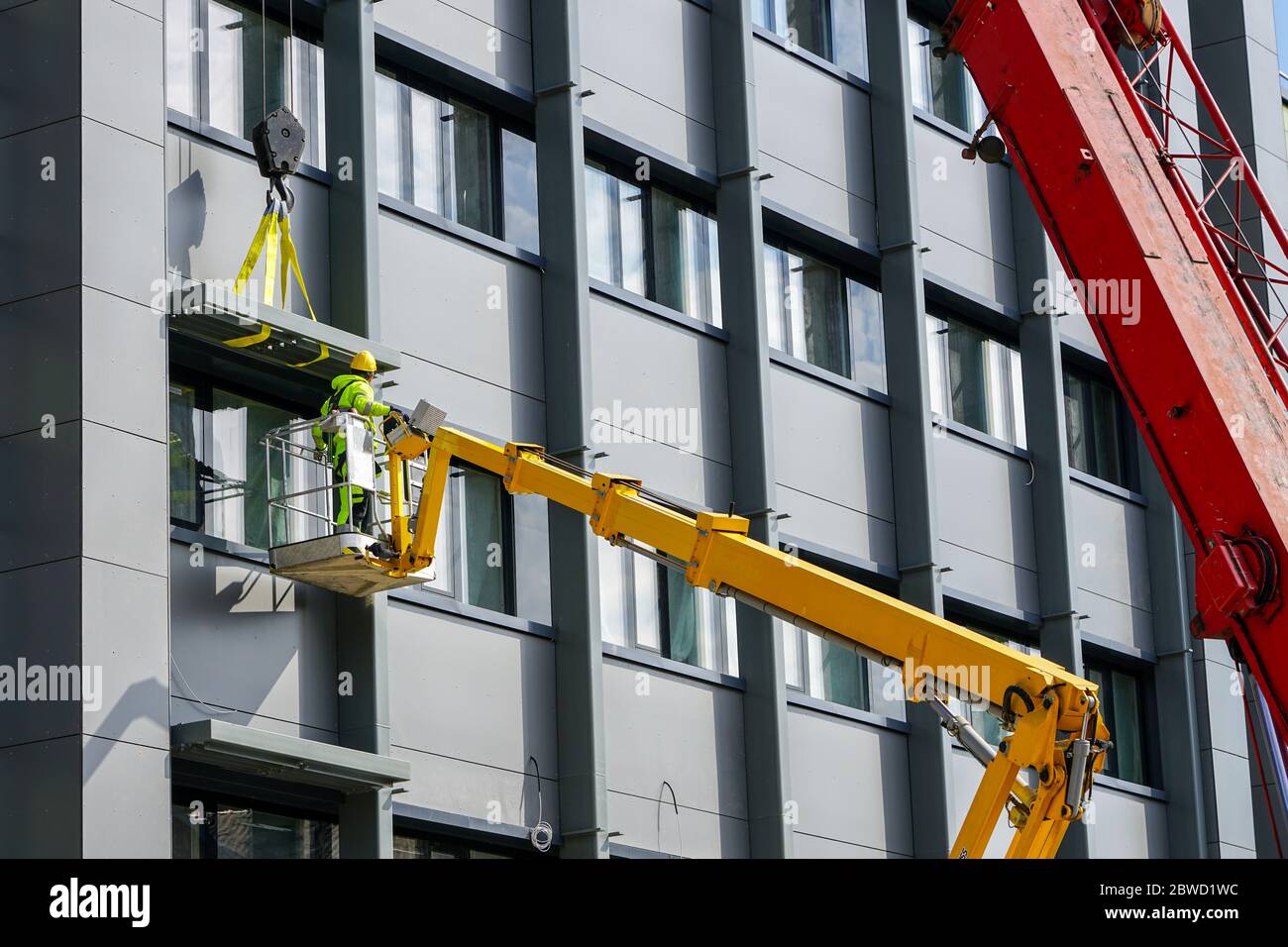 attaching the finishing element of the house facade using a scissor lift Stock Photo
