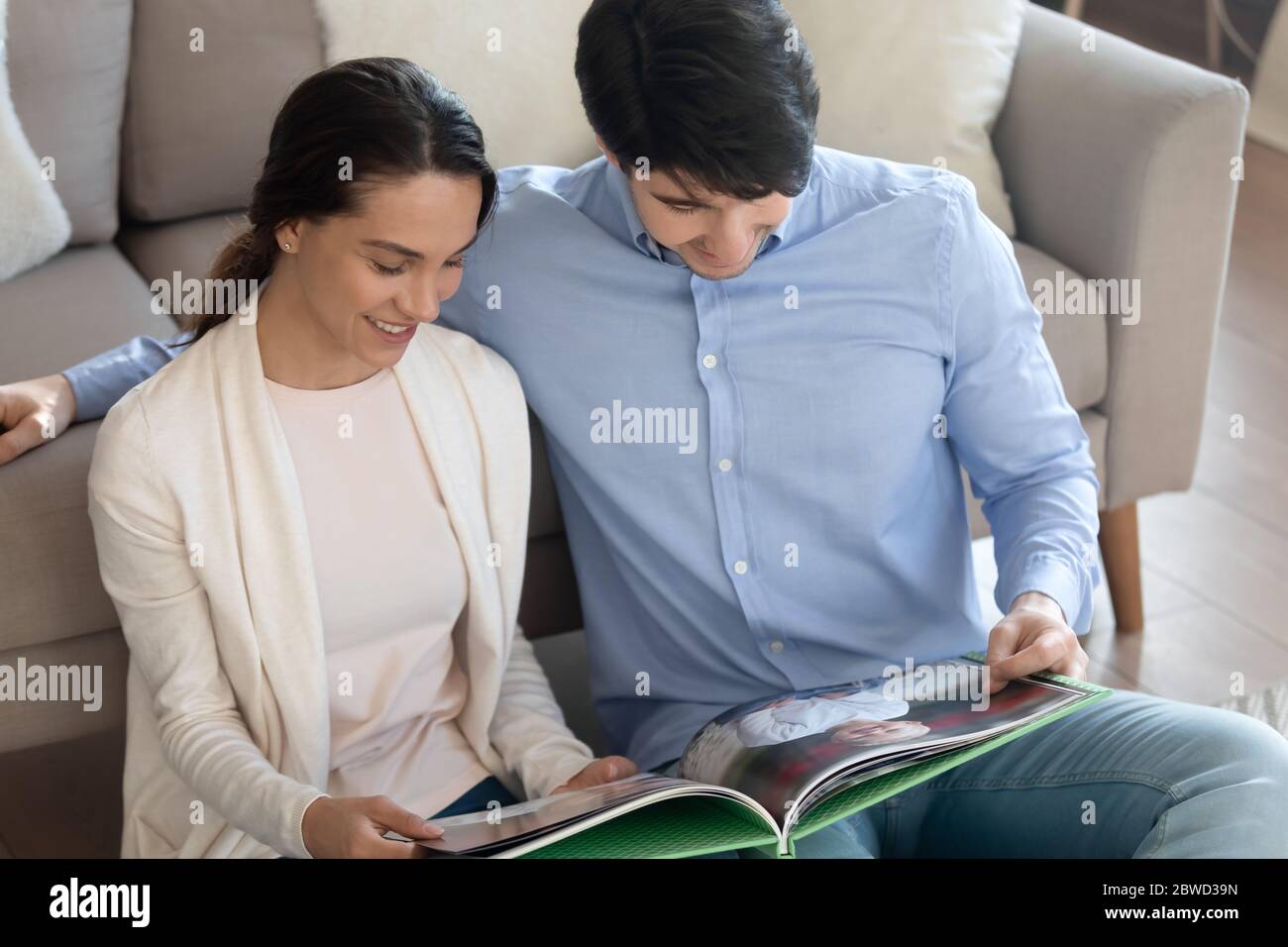 Happy young couple look at children photos in album Stock Photo