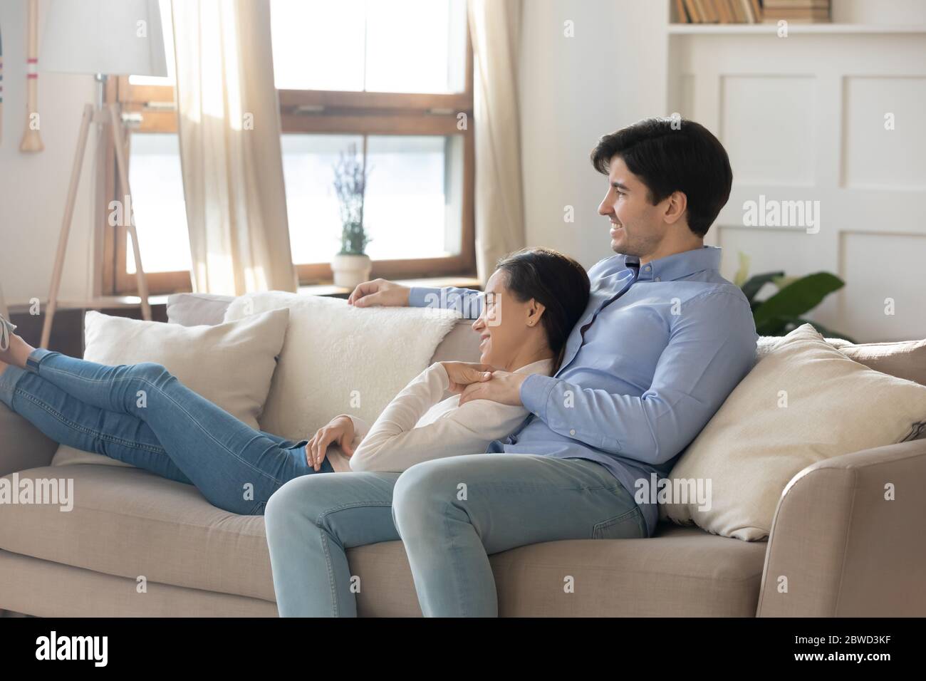 Happy couple relax on sofa cuddling and hugging Stock Photo