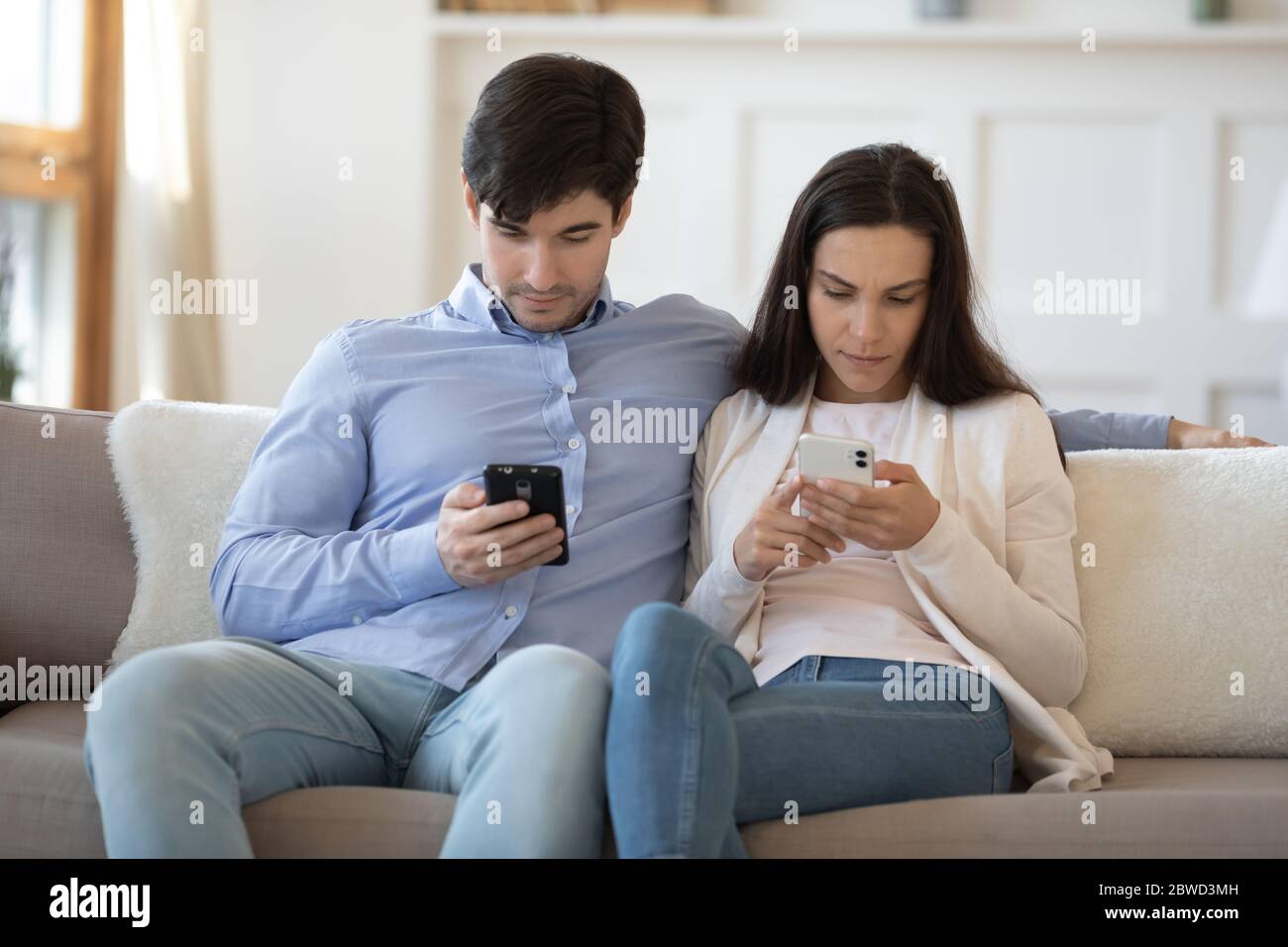 Young couple relax on couch using modern smartphones Stock Photo