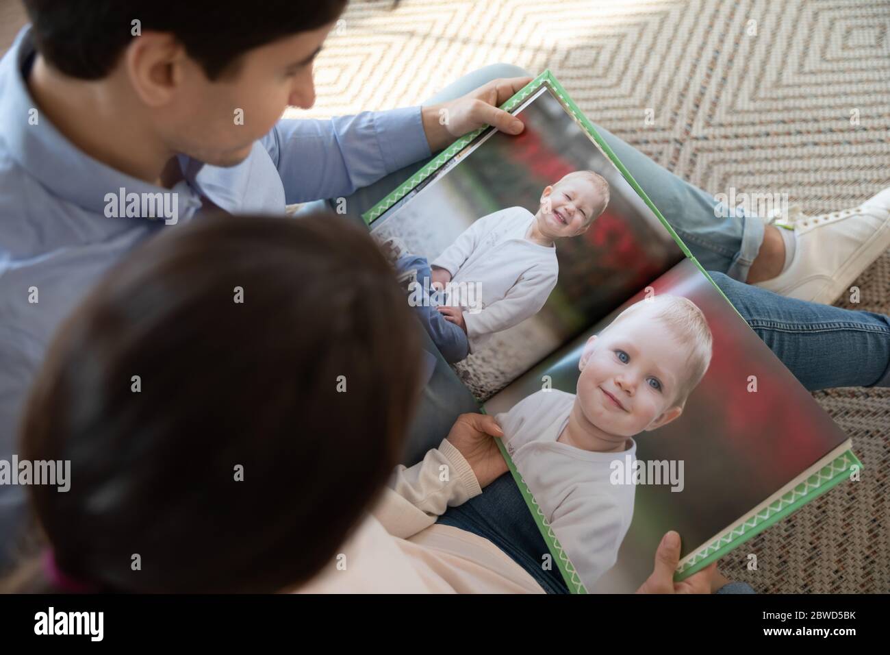 Young couple enjoy childhood kid photos in album Stock Photo