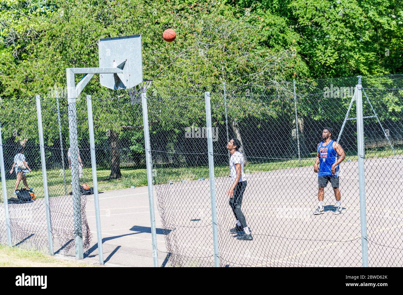 Young adults playing basketball on Sunny day Stock Photo