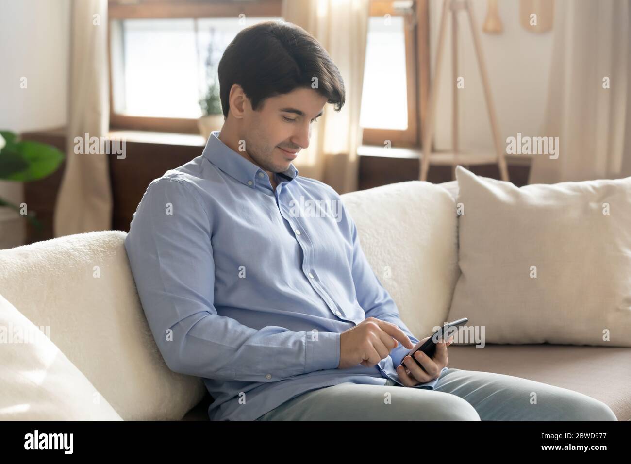Young man relax on couch using smartphone Stock Photo