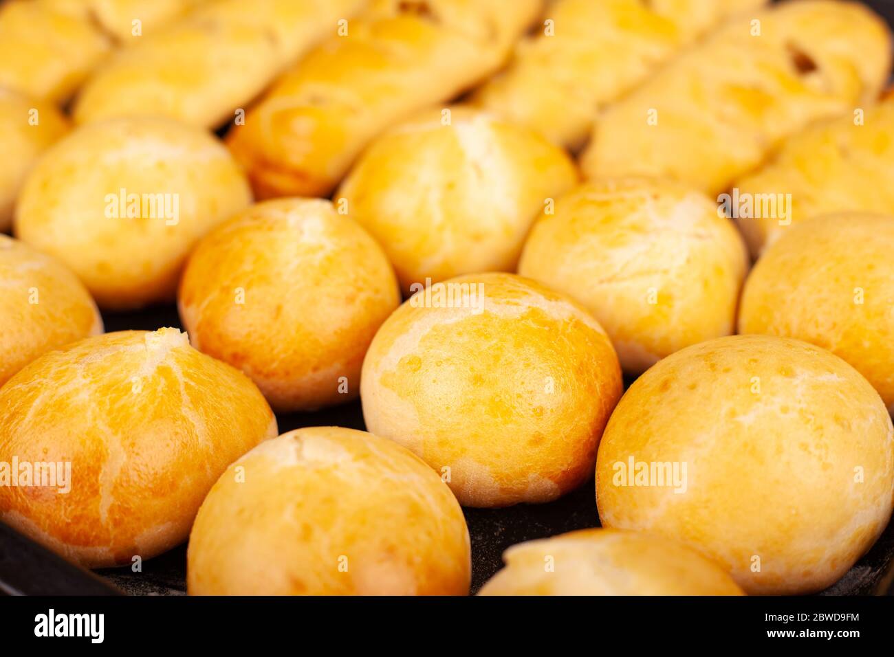 round hot baked buns with a golden crust on a baking sheet closeup