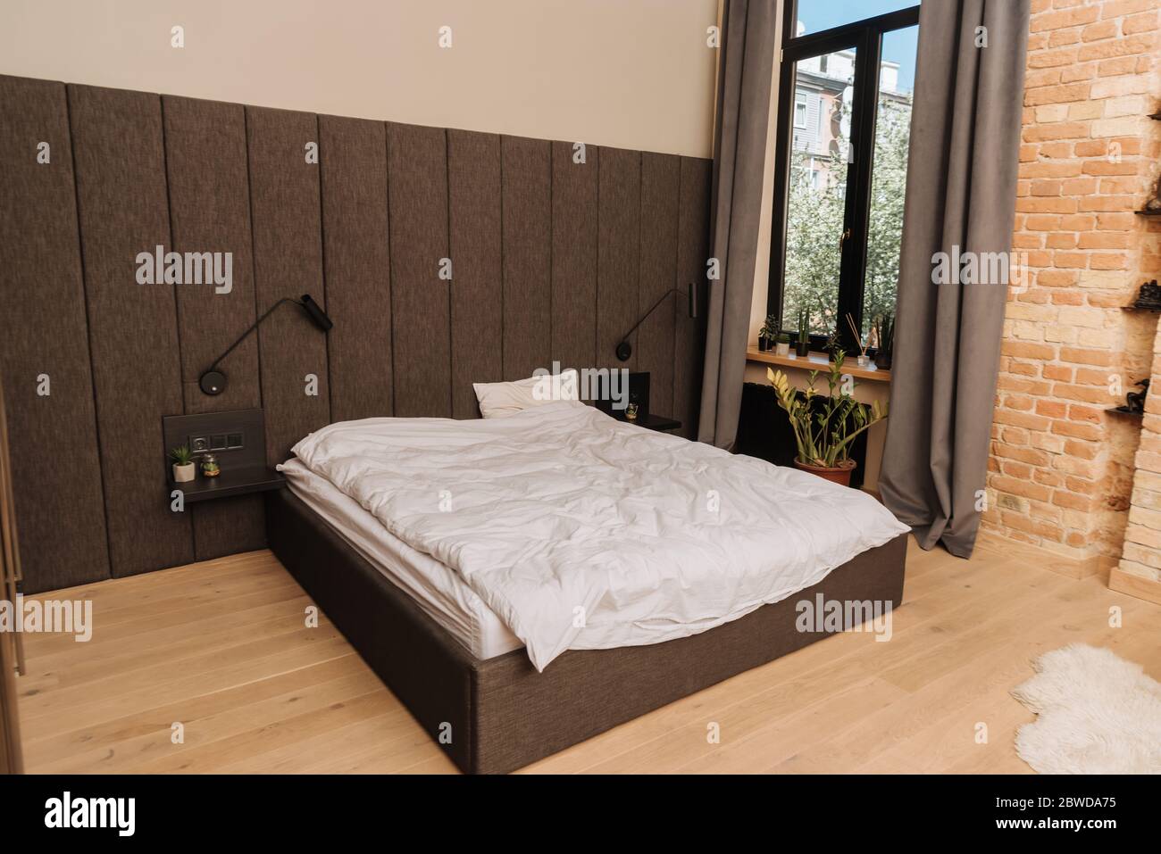spacious bedroom with large bed, dark curtains on window and potted plants  on windowsill Stock Photo - Alamy