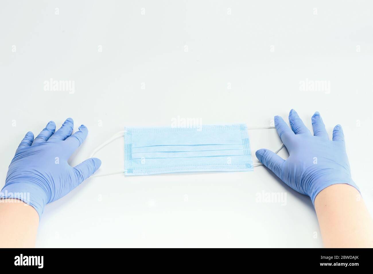 Hands  in gloves holding surgical mask. Coronavirus outbreak concept. Healthcare concept. Horizontal with space for text. Stock Photo