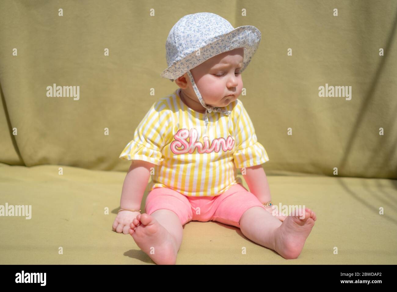 Cute baby girl wear adorable hat looking at camera make funny faces on green background Stock Photo