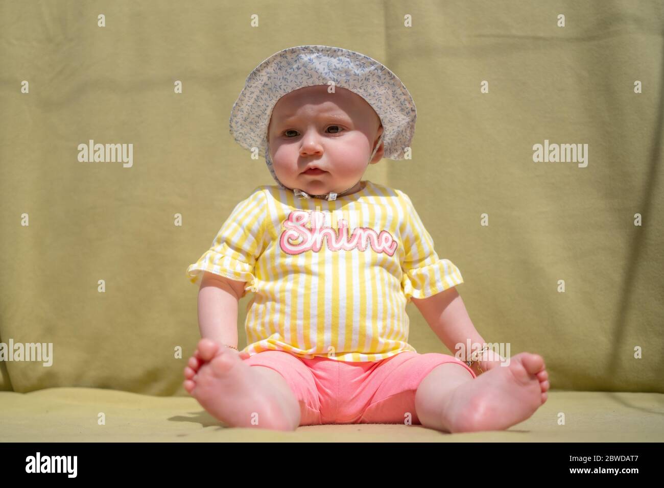 Cute baby girl wear adorable hat looking at camera make funny faces on green background Stock Photo