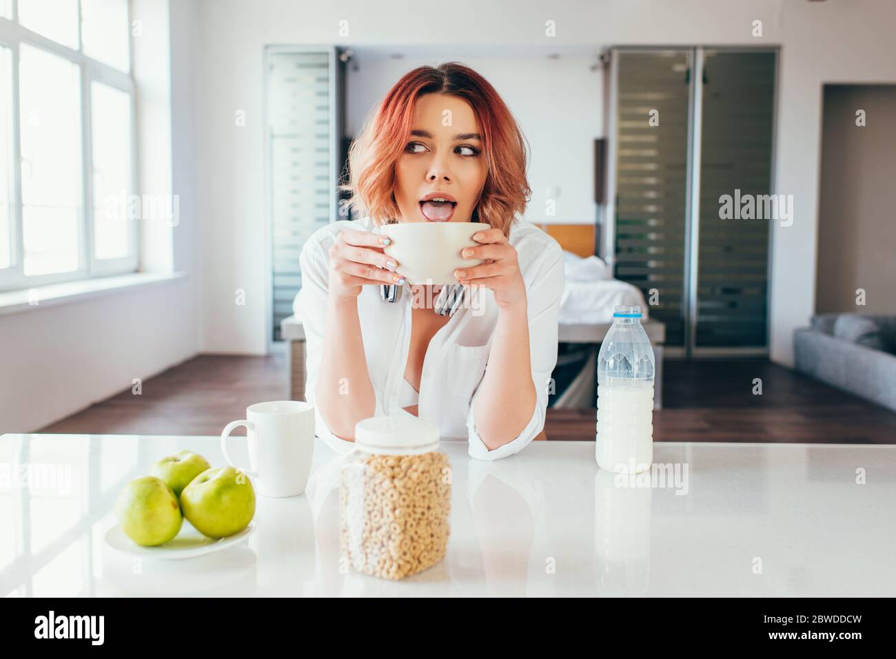 attractive girl licking cornflakes with milk for breakfast during quarantine Stock Photo
