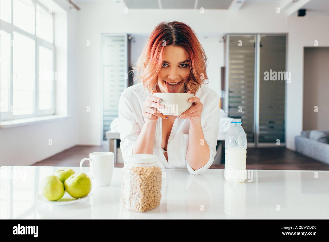 funny girl licking cornflakes with milk for breakfast during quarantine Stock Photo