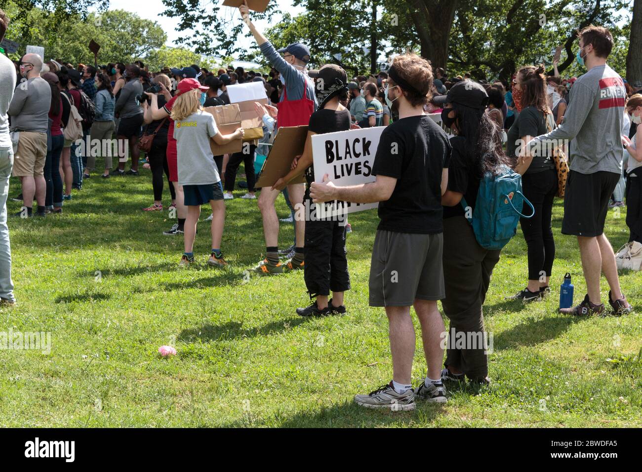 a caucasian man holds a Black Lives Matter sign at the protest or vigil on the Cloisters Lawn in Fort Tryon Park Stock Photo