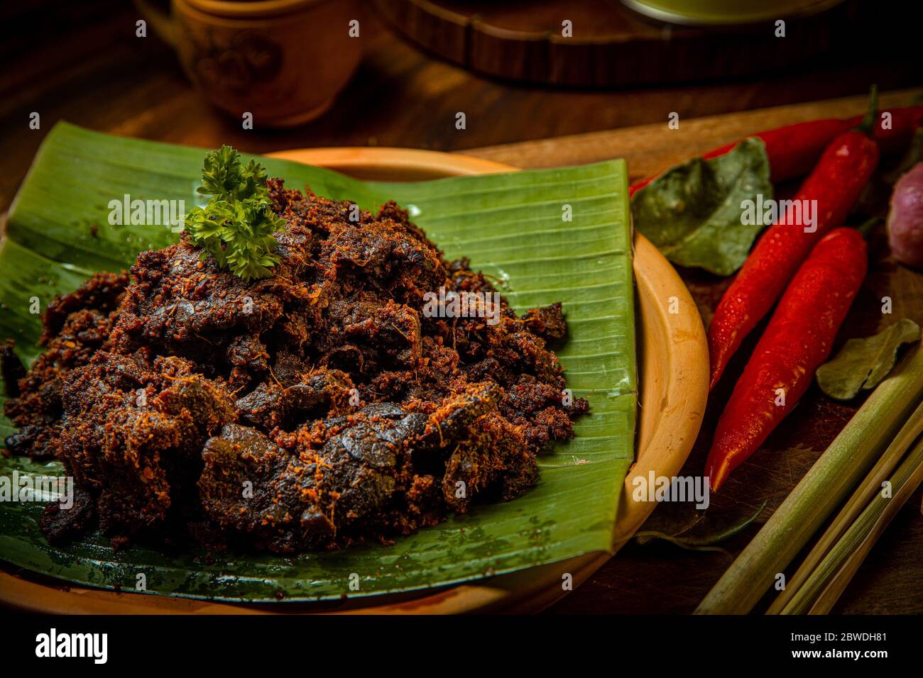 Rendang Paru or Spicy Beef Lung stew traditional food from Padang, Indonesia. The dish is arranged among the spices and herbs Stock Photo