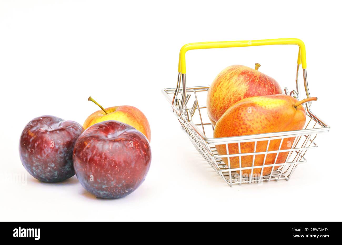a small shopping basket with fruits, apples, pears and plums on a white background. Healthy food, vegetarian food, vegetables, shopping at the superma Stock Photo