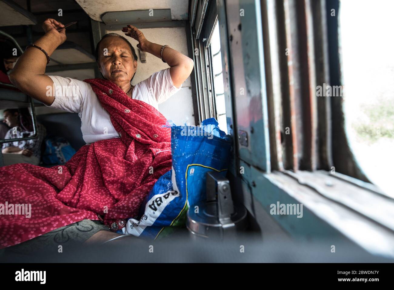 Woman looking out moving train window, second class train. Indian Railways. India. Stock Photo
