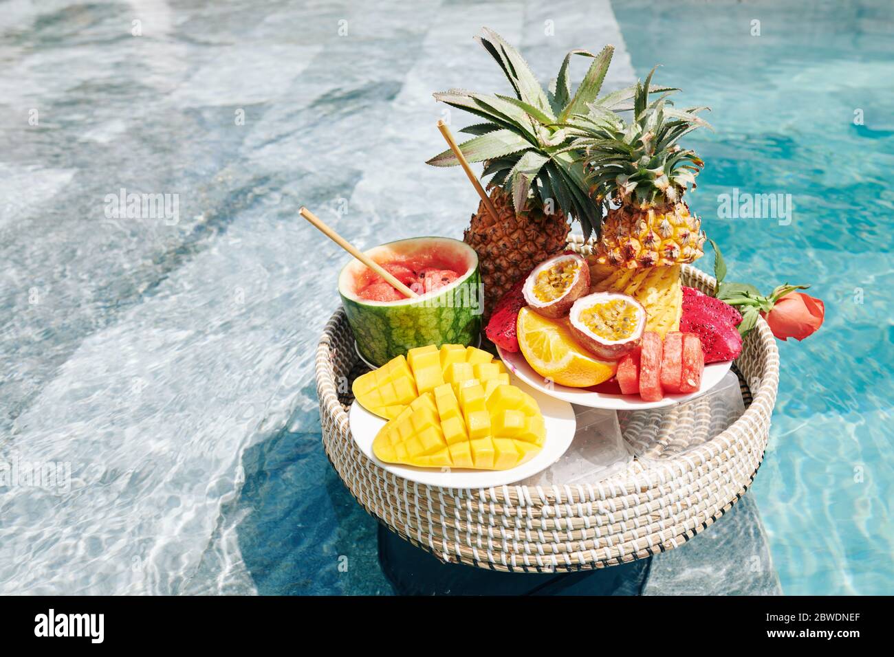 Various delicious exotic fruits on wicker tray floating in swimming
