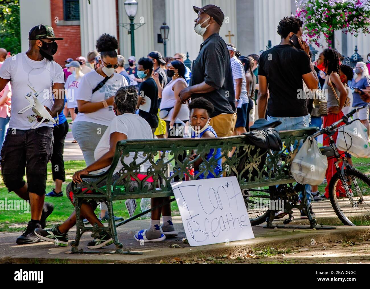 A boy sits on a bench beside an “I Can’t Breathe” sign during a vigil for George Floyd at Cathedral Square, May 31, 2020, in Mobile, Alabama. Stock Photo