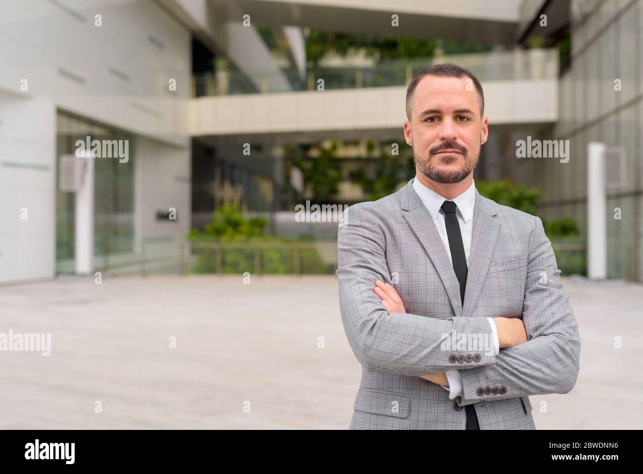 Handsome Hispanic bald bearded businessman with arms crossed in the ...