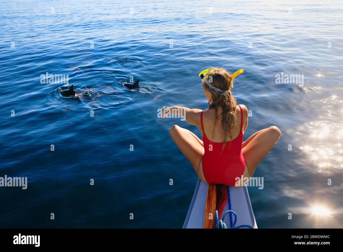 Young happy girl in snorkeling mask sit no boat. Dolphins watching adventure tour on tropical islands. Water activity, active children lifestyle Stock Photo