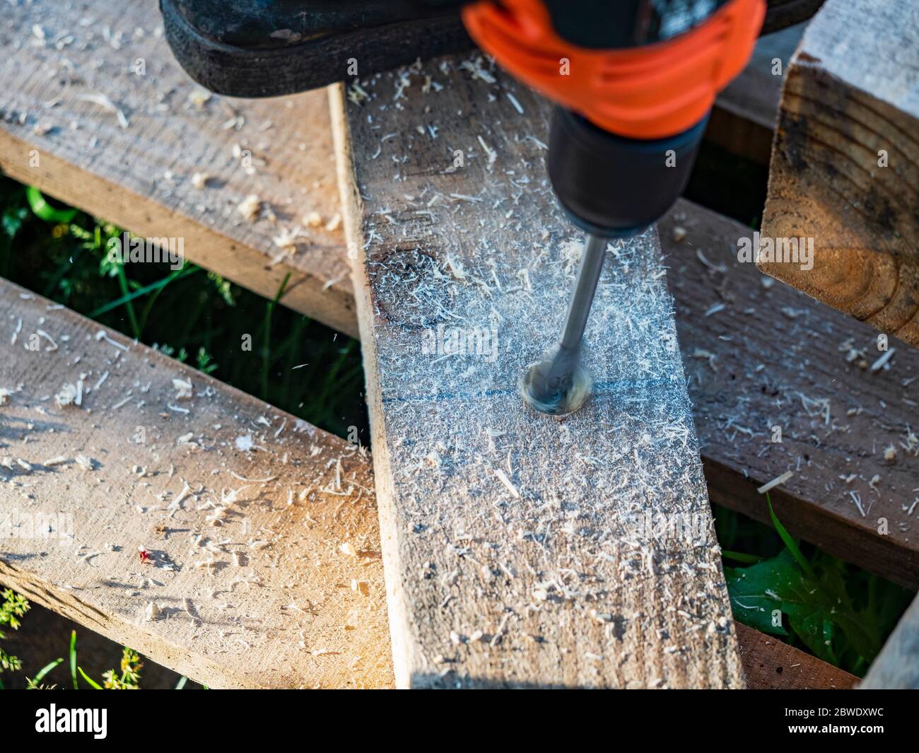 Making holes in a pine beam using an electric drill with wood drilling
