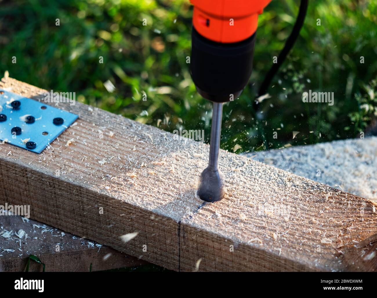 Making holes in a pine beam using an electric drill with wood drilling bit Stock Photo