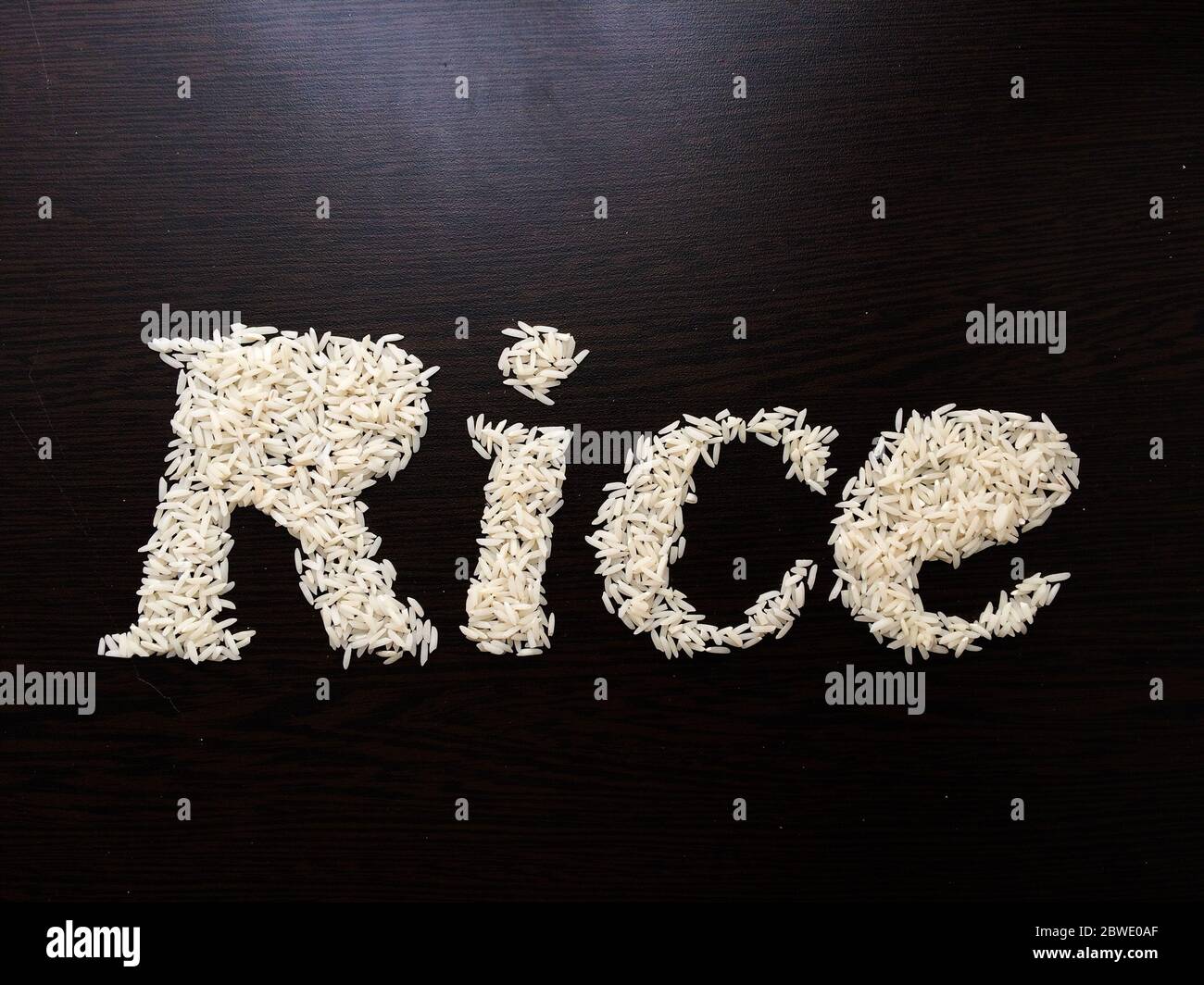 Writing the word Rice with rice seeds on a table with brown wooden