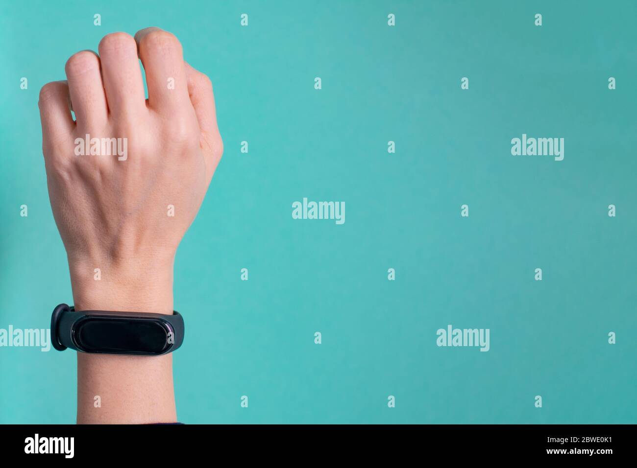 Black fitness bracelet for sports training on a girls hand on mint background. Selective focus. Stock Photo