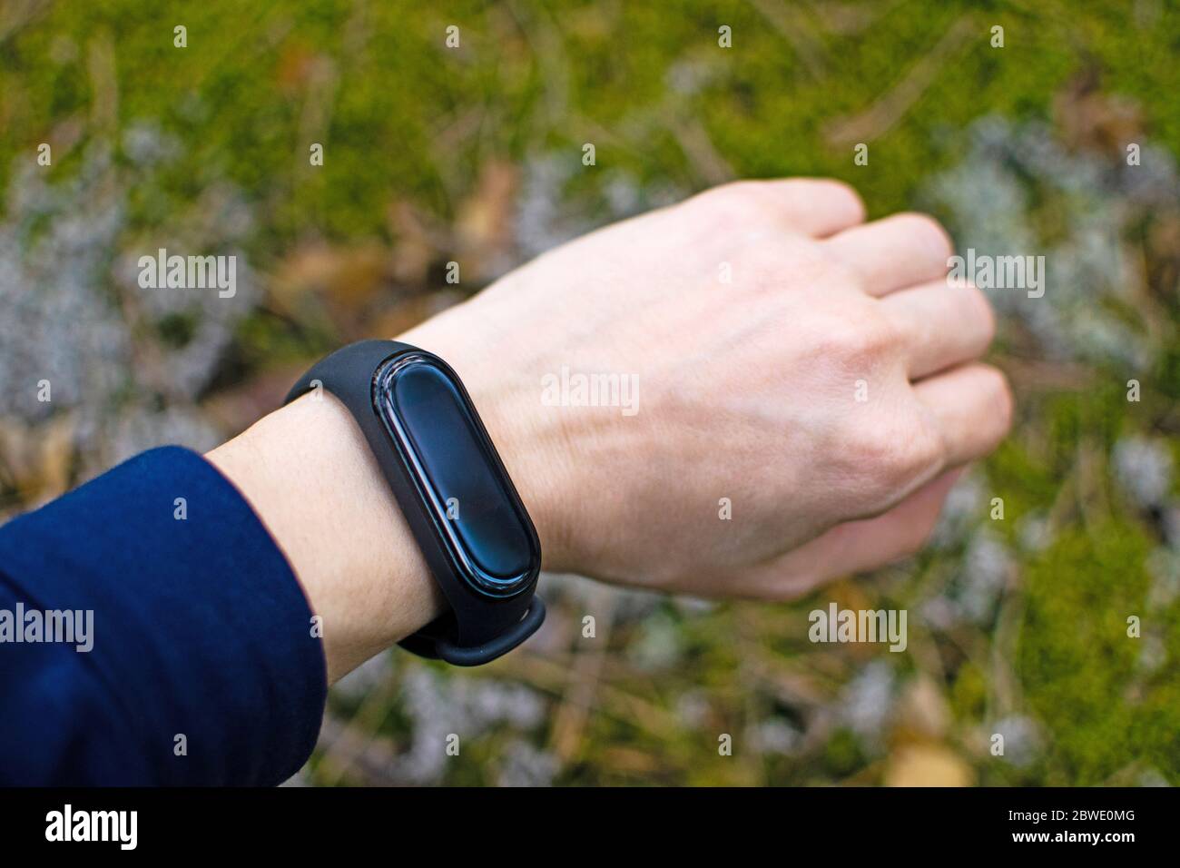 Black fitness bracelet for sports training on a girls hand on a natural background. Sports in the forest. Selective focus. Stock Photo