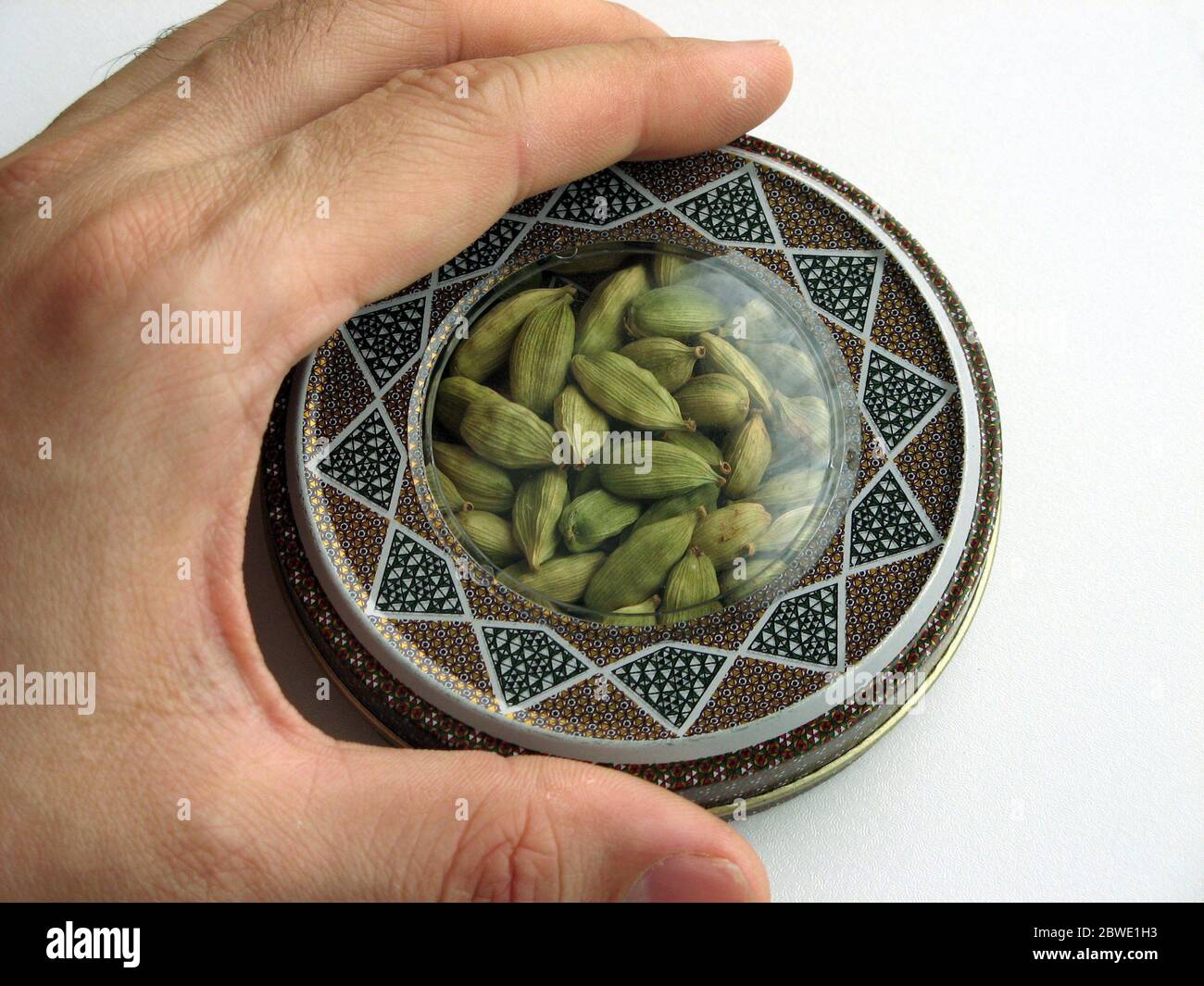 mashhad, IRAN, 01 03 2020: Green cardamom pods into handcraft box. Hand on box. Close up. Stock Photo