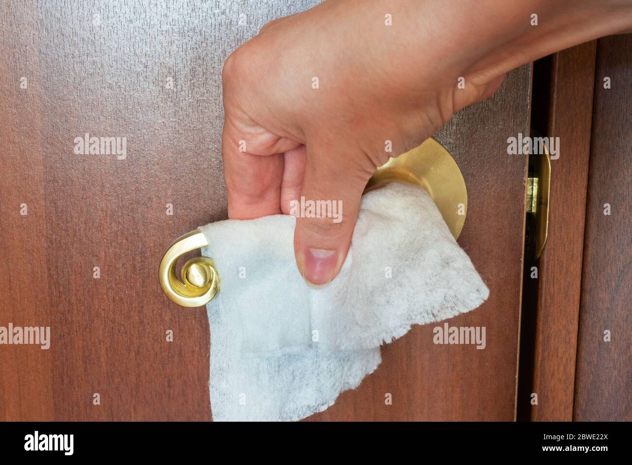 woman cleans the door handle with a napkin. Disinfection of surface