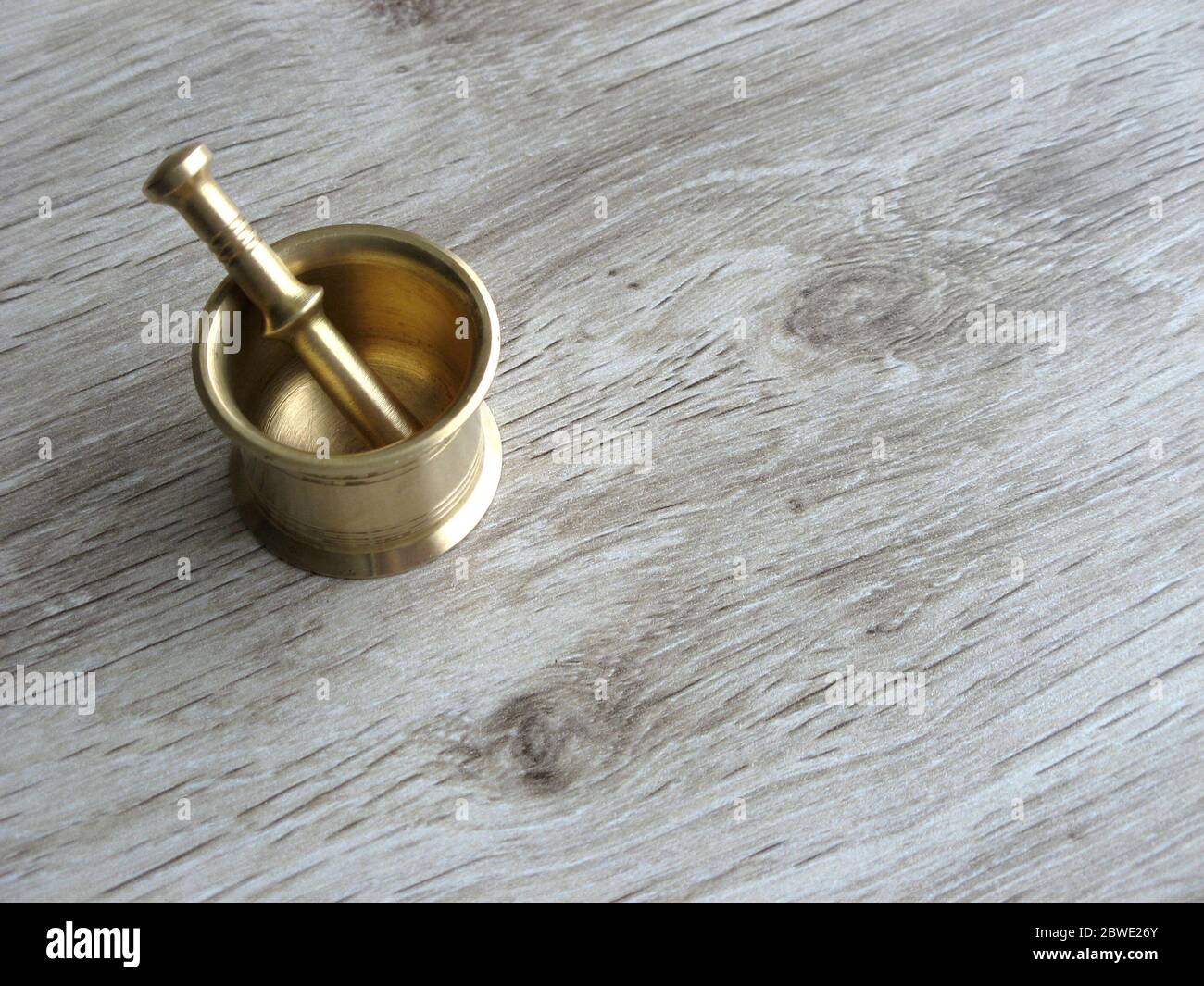 Mini brass Mortar and Pestle on wooden background with space for text