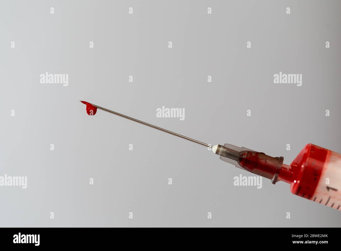 Syringe with a blood sample. A drop of blood at the end of the needle