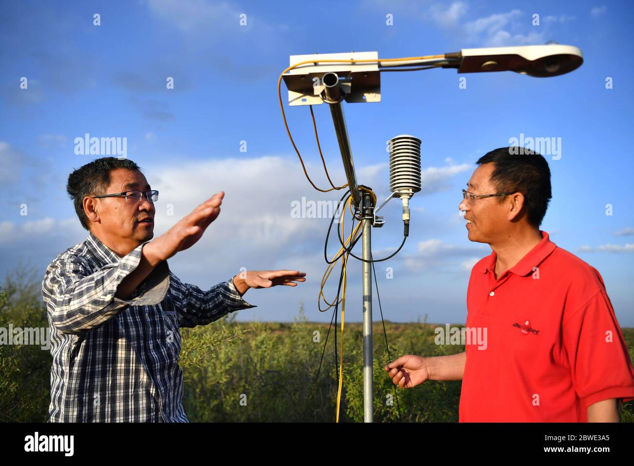 (200601) -- SHENMU, June 1, 2020 (Xinhua) -- Zhang Yinglong (R) and a scientist discuss about soil moisture at Gechougou Village, Shenmu County of northwest China's Shaanxi Province, May 27, 2020. In 2003, Zhang Yinglong resigned his work and returned to his hometown Shenmu County, which located in an isolated desert. He contracted a land of 192,000 Mu (about 12,800 hectares) and made up his mind to plant trees and control sands here. Over the 17 years, Zhang has contracted accumulated 428,000 Mu (about 28,533 hectares) of lands and developed ecological planting and livestock raising industrie Stock Photo