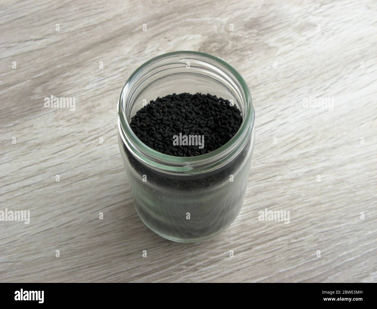 Nigella seeds or Black cumin or Black onion seed, and Black sesame seed  into glass jar on wooden. Useful for skin and hair Stock Photo - Alamy