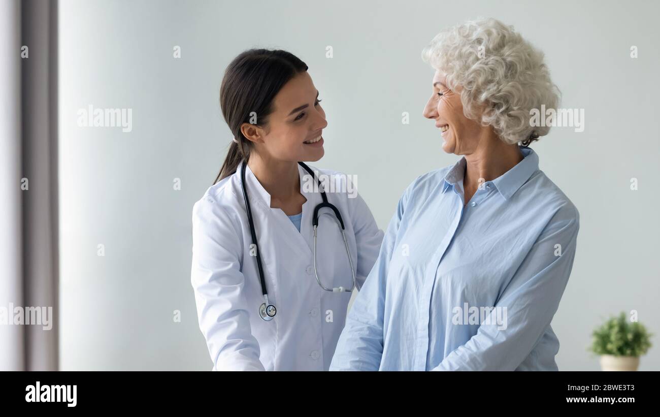 Caring nurse smiling looking at old woman patient showing support Stock Photo