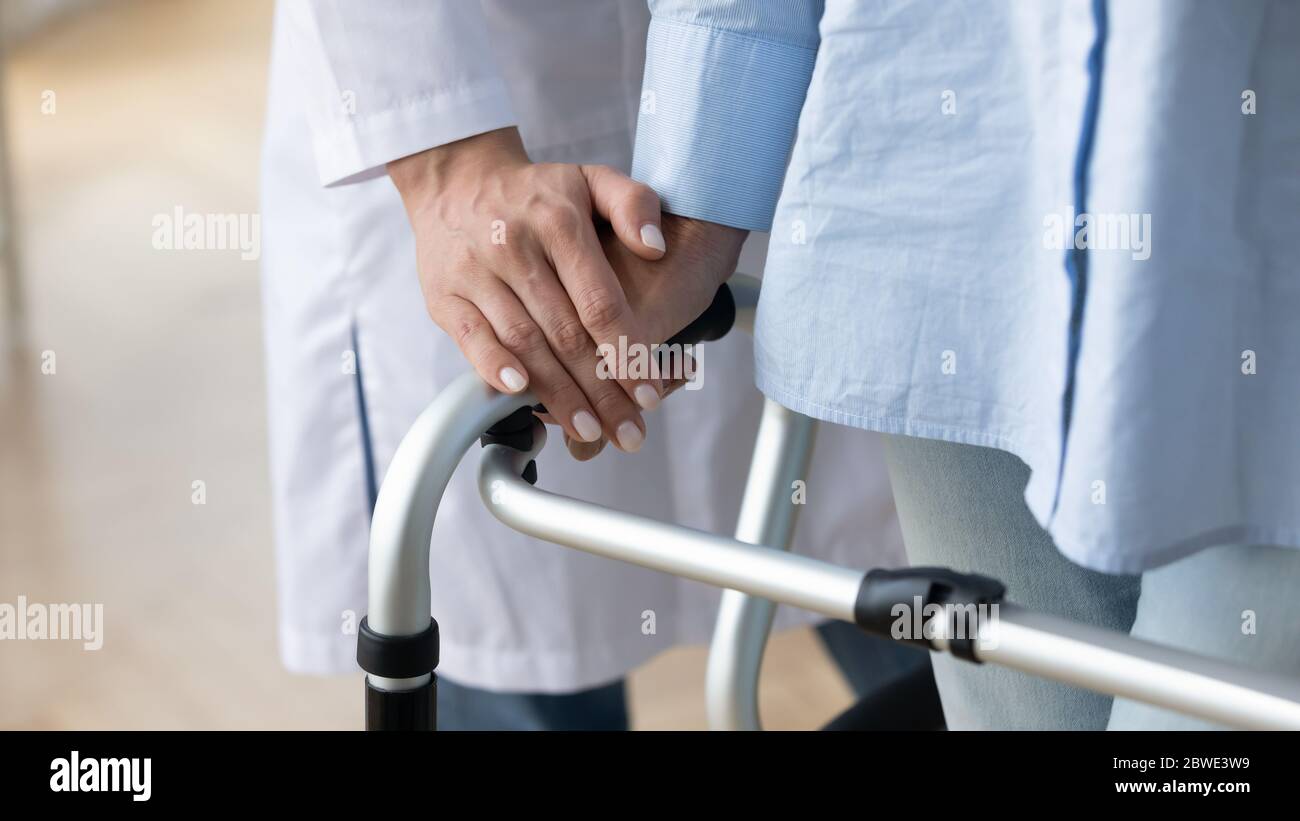 Physical therapist helping to old patient walking with rollator closeup Stock Photo