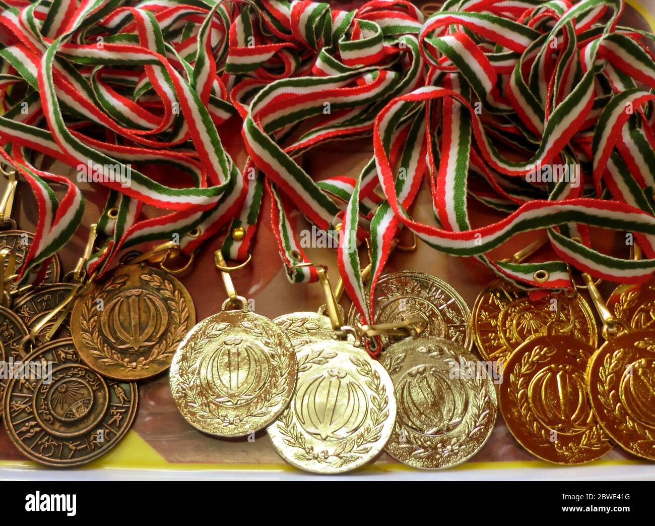 Golden, silver, bronze sports medal with red, white and green ribbon. Winner awards. Translation of the text on medals are ' islamic republic of iran. Stock Photo