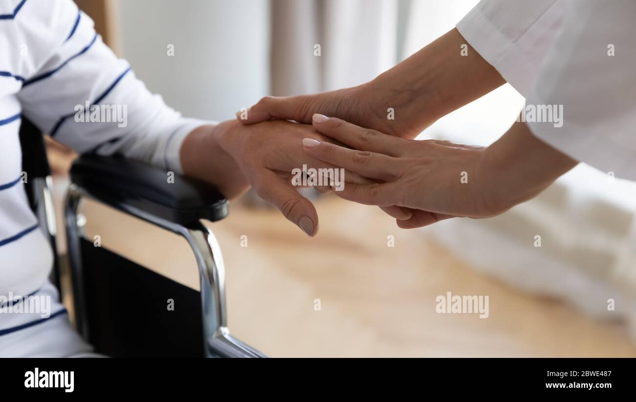 Disabled elderly woman sitting in wheelchair her palm holding nurse Stock Photo