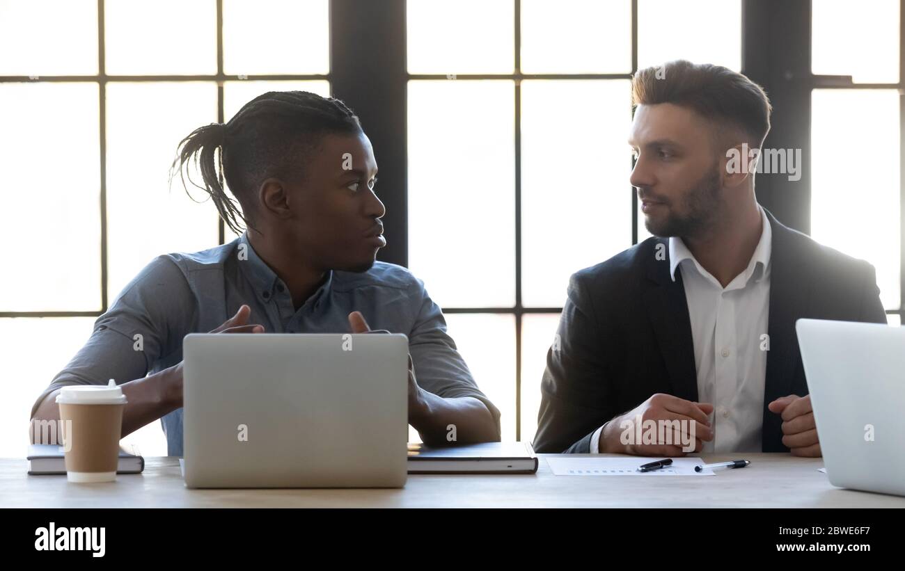 Diverse colleagues working on project together, sharing ideas, using laptops Stock Photo