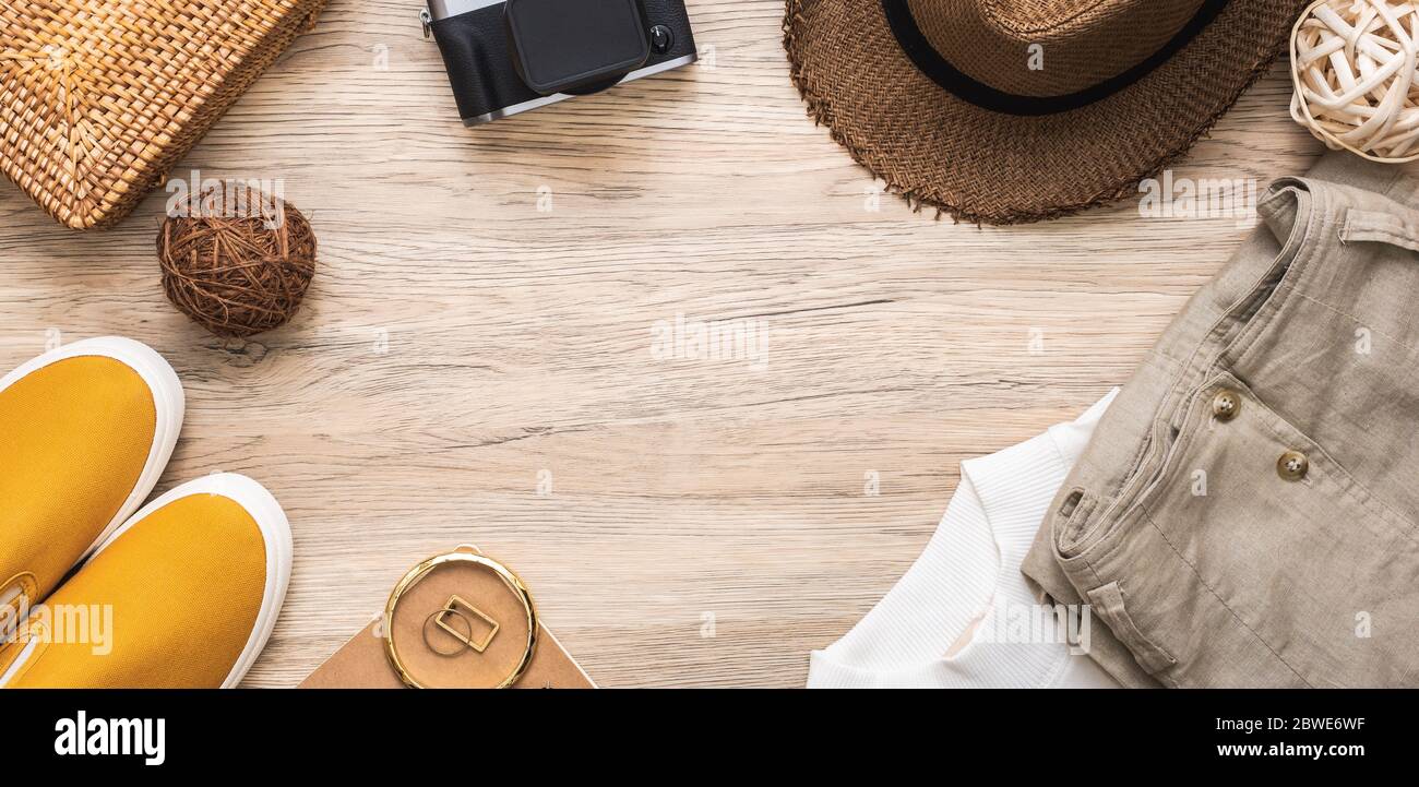 summer travel flat lay of traveller accessories set.cloth,hat,wicker bag,canvas shoe,camera and notebook on wooden table with copy space Stock Photo