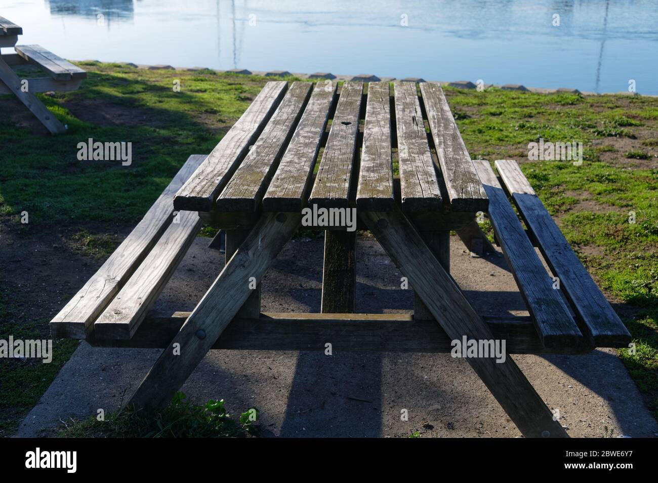 A great place for a picnic, a wooden table with bench seats sits in front of the sea Stock Photo