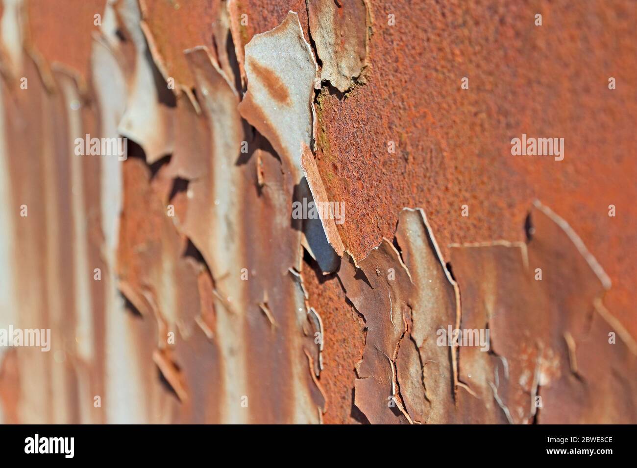 Peeling stained grey paint revealing rusty texture beneath Stock Photo