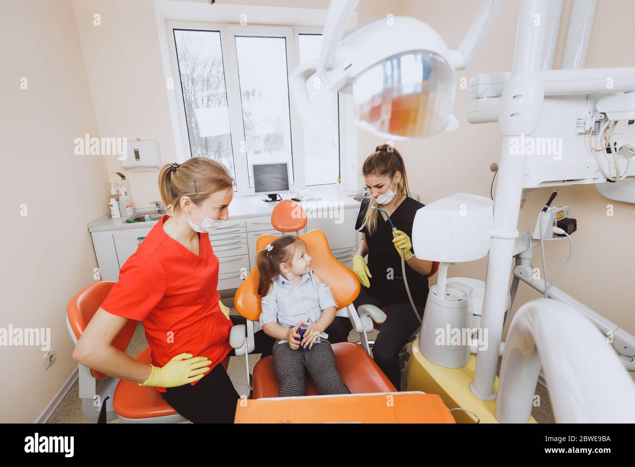 Female doctor and assistant explaining curing procedure to little girl ...