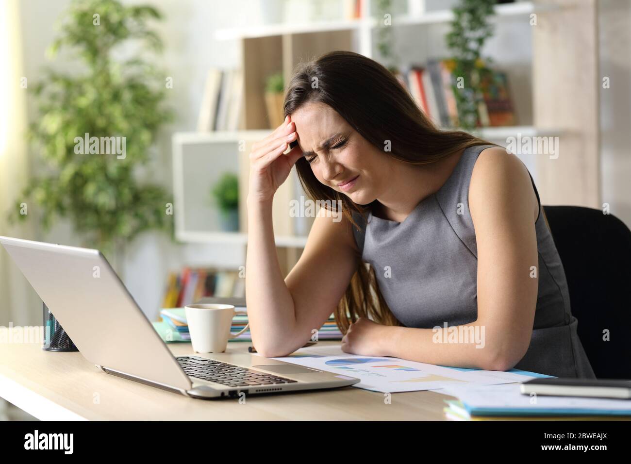 Entrepreneur woman suffering painful headache sitting on a desk at homeoffice Stock Photo