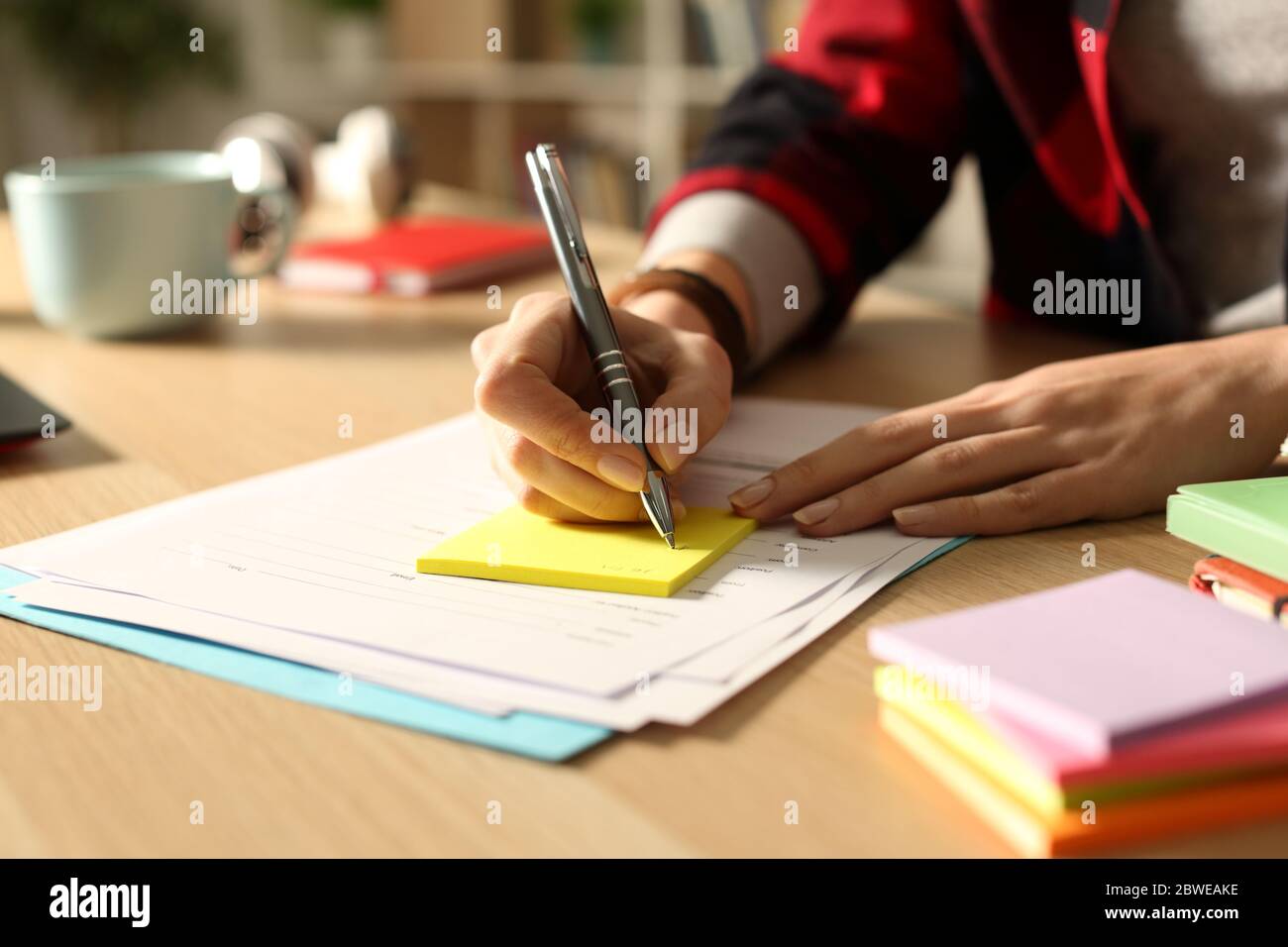Close up of student girl hand writing on post note on a desk at night Stock Photo