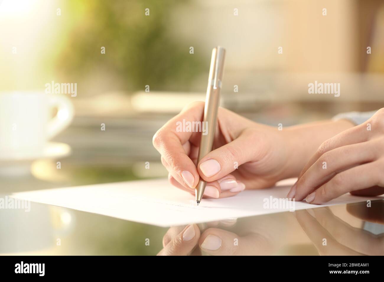 Close up of woman hand writing on a paper on a desk at home Stock Photo