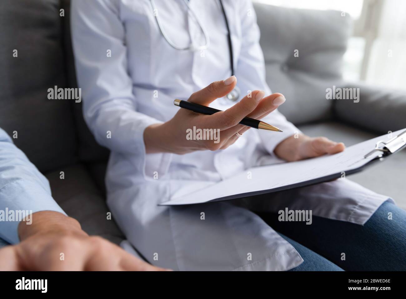 Closeup view female therapist holding clipboard talking to elderly patient Stock Photo
