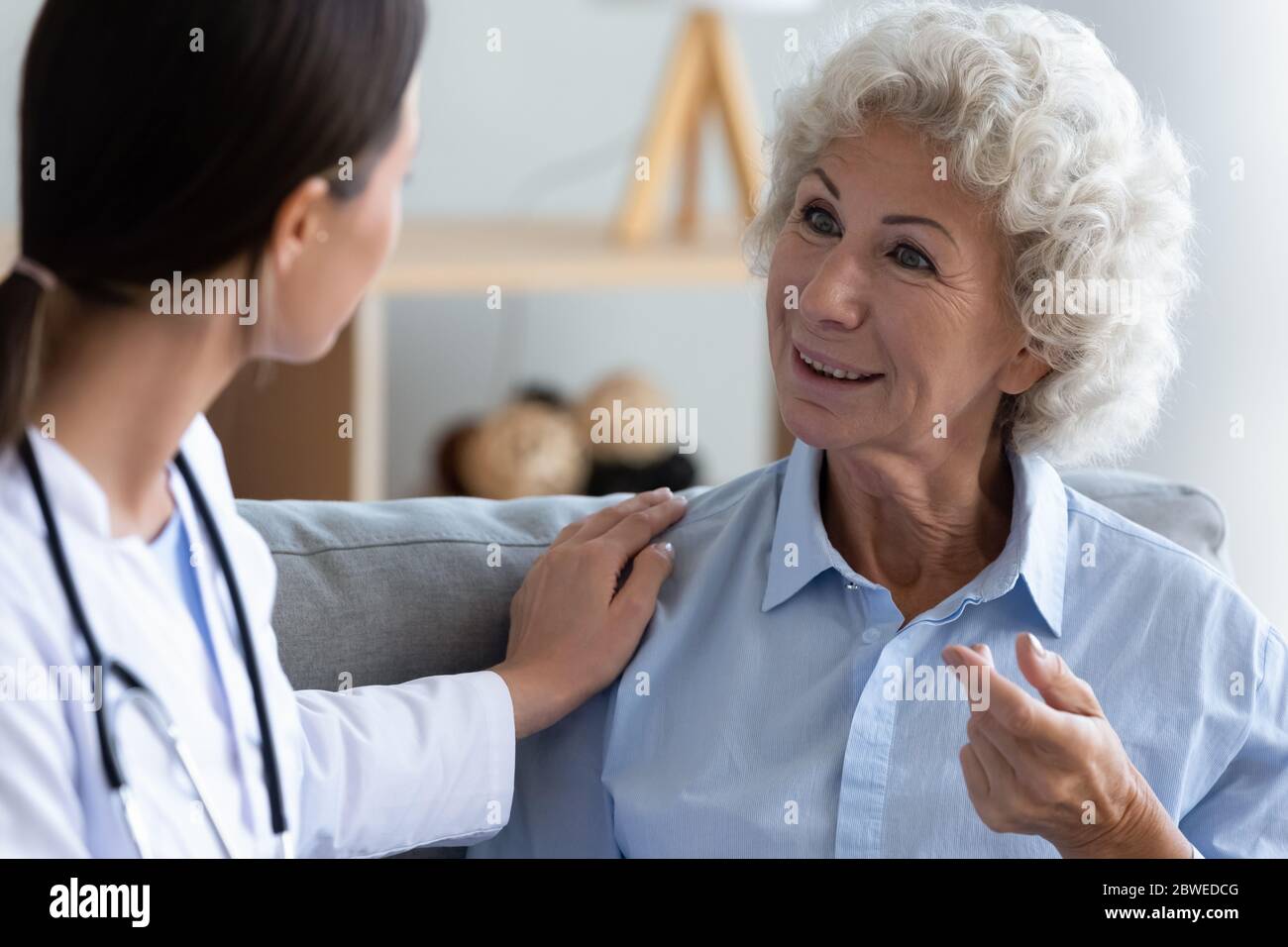 Elderly woman patient talk to young medic in white coat Stock Photo