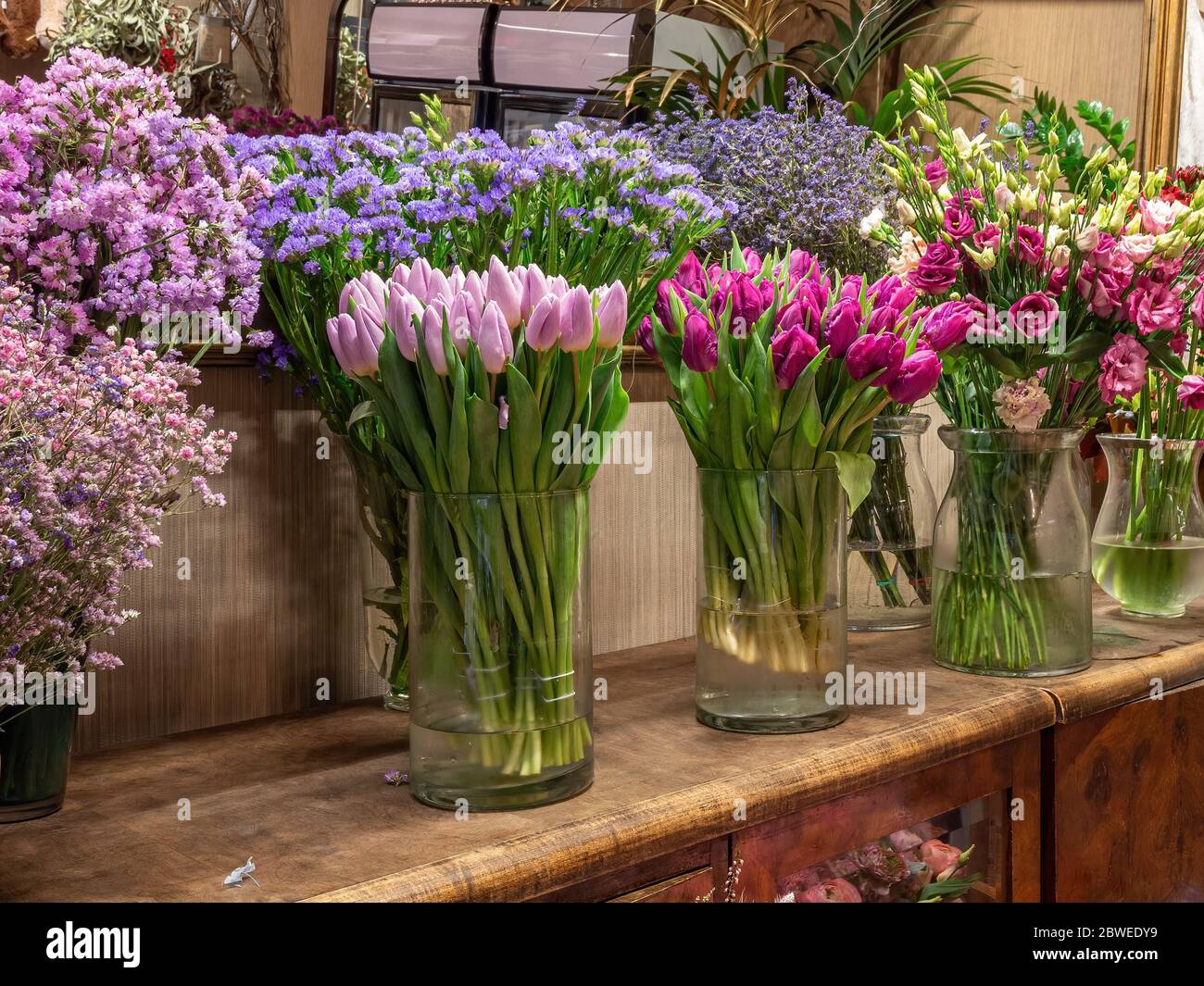 Beautiful colorful flowers for sale, placed in vases in flower shop. Tulips, roses and limonium Stock Photo