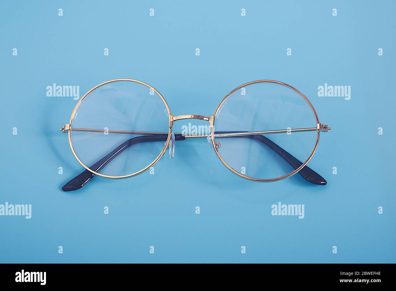 Stylish Gold black glasses isolated on blue vintage background Stock Photo